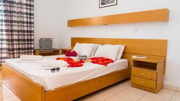 Una cama bien hecha con sábanas blancas, un cabecero de madera y una mesita de noche con una lámpara.