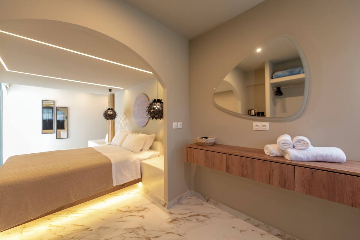 Un dormitorio moderno con una cama, un tocador con espejo y un baño con ducha.