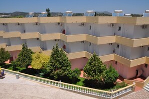 A multi-story building with solar panels on the roof, a central courtyard with trees, and a tiled floor.