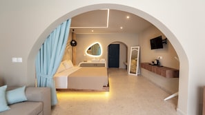 Quarto moderno com uma cama grande, banheiro com espelho e televisão na parede.