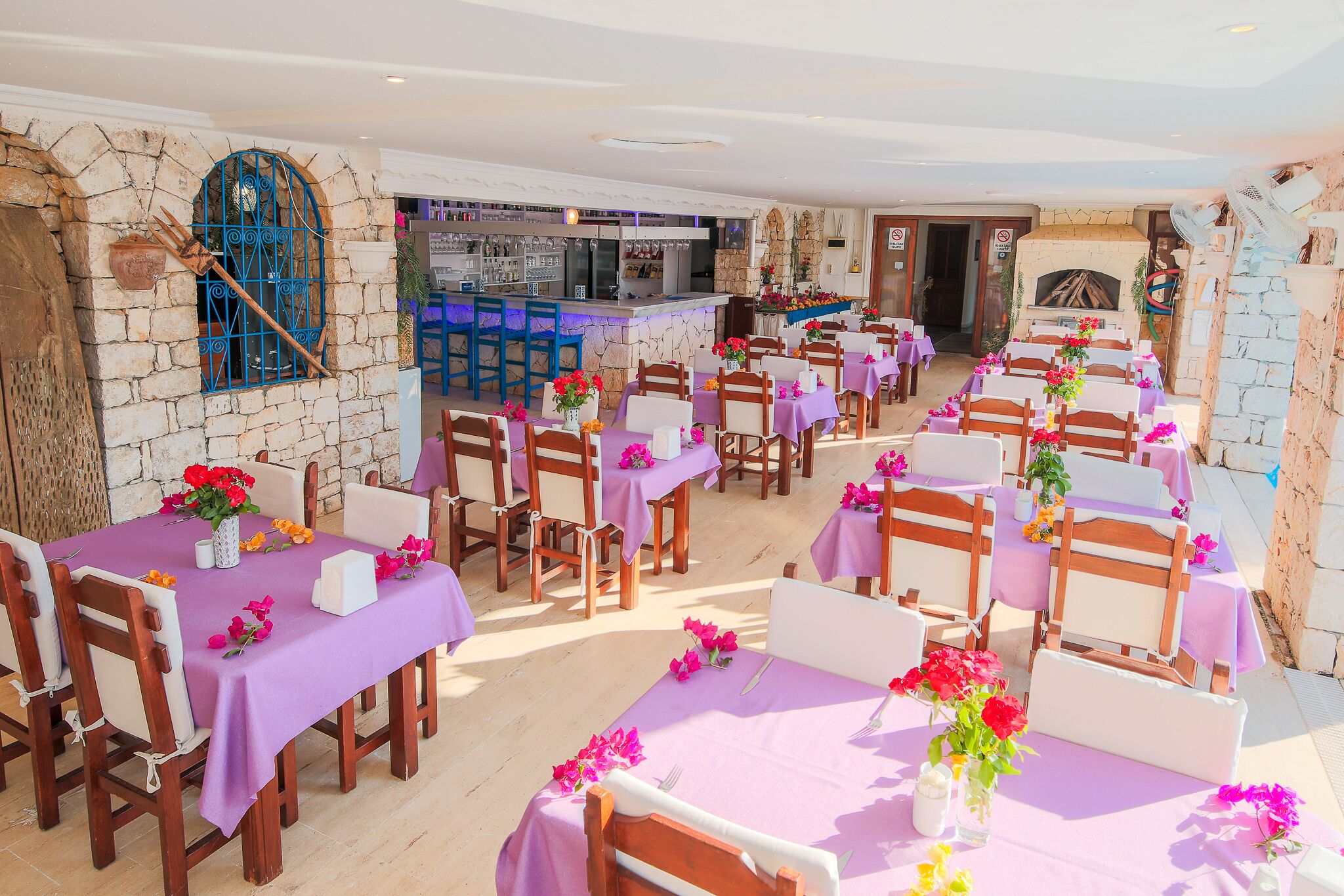 Un restaurante con paredes de piedra, mesas de madera y manteles morados.