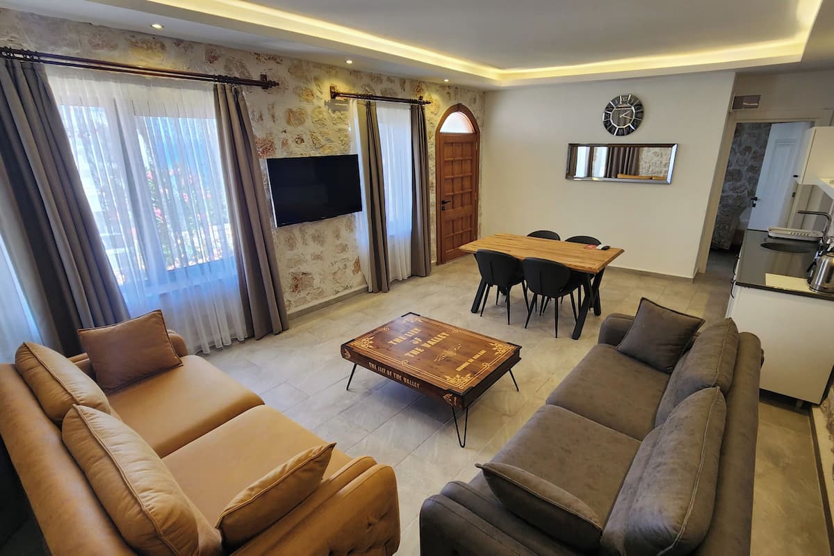 Una sala de estar con sofá, mesa de centro, televisión y comedor con sillas y mesa.