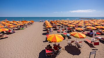 Una playa cerca, sillas reclinables de playa, sombrillas