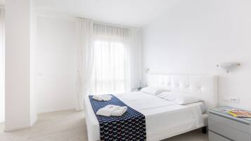 Una camera da letto ordinata con un letto, un comodino e una finestra con tende.