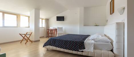 A bedroom with a bed, a TV, a chair, and a table.