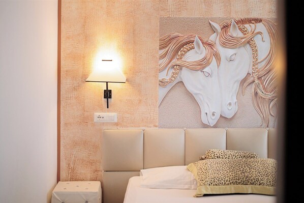 A hotel room with a bed, a wall-mounted lamp, and a decorative horse mural.