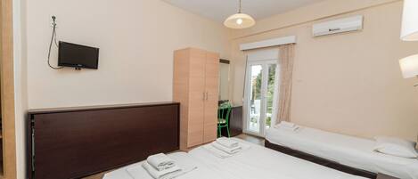Habitación de hotel con dos camas, televisión, armario y balcón con una silla.