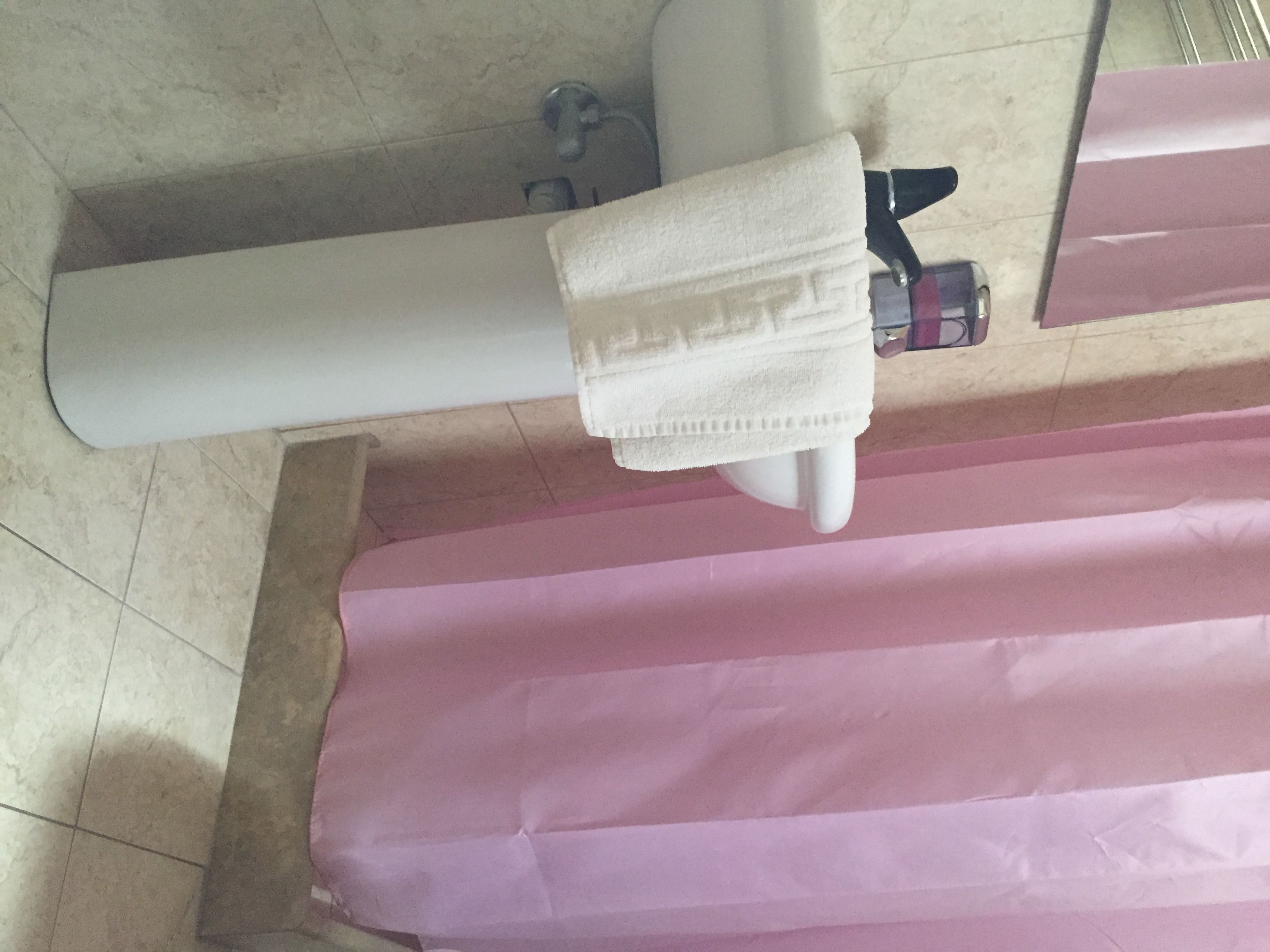 A bathroom with a white bathtub, a pink shower curtain, and a white towel hanging on a towel rack.