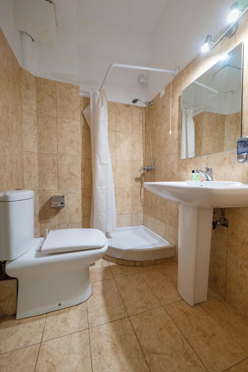 A bathroom with a toilet, shower, and sink.