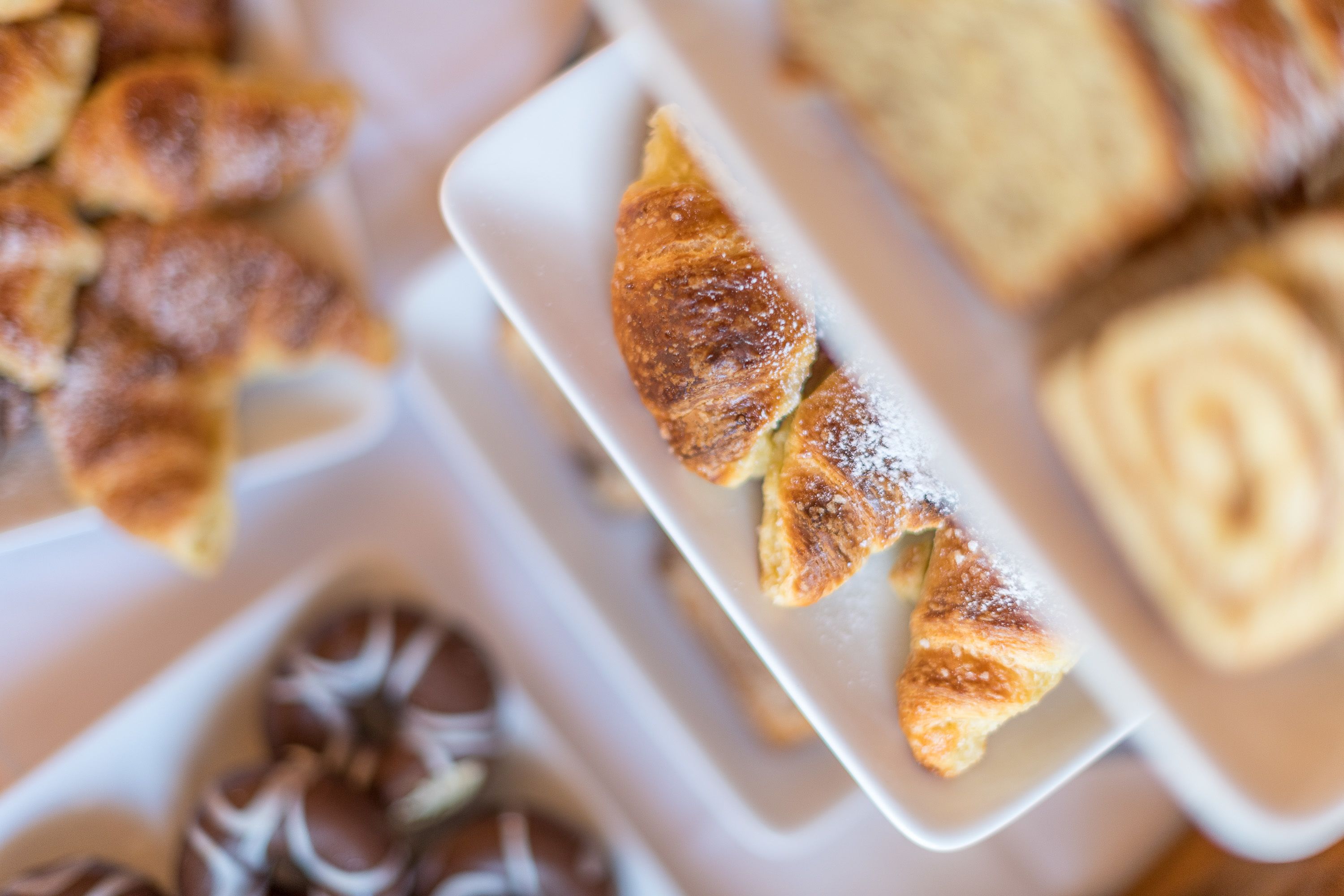 A tray of pastries, including croissants and chocolate-covered items, on a white plate.