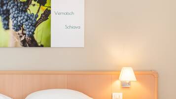 A hotel room with a bed, a nightstand with a lamp, and a wall-mounted sign with text.