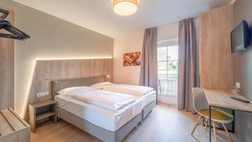 Una camera d'albergo moderna con un letto, un comodino, una scrivania, una sedia e una televisione.