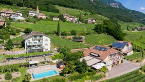 A hillside property with a swimming pool, solar panels, and vineyard views. - Garni Hotel Ritterhof (Termeno Sulla Strada del Vino)