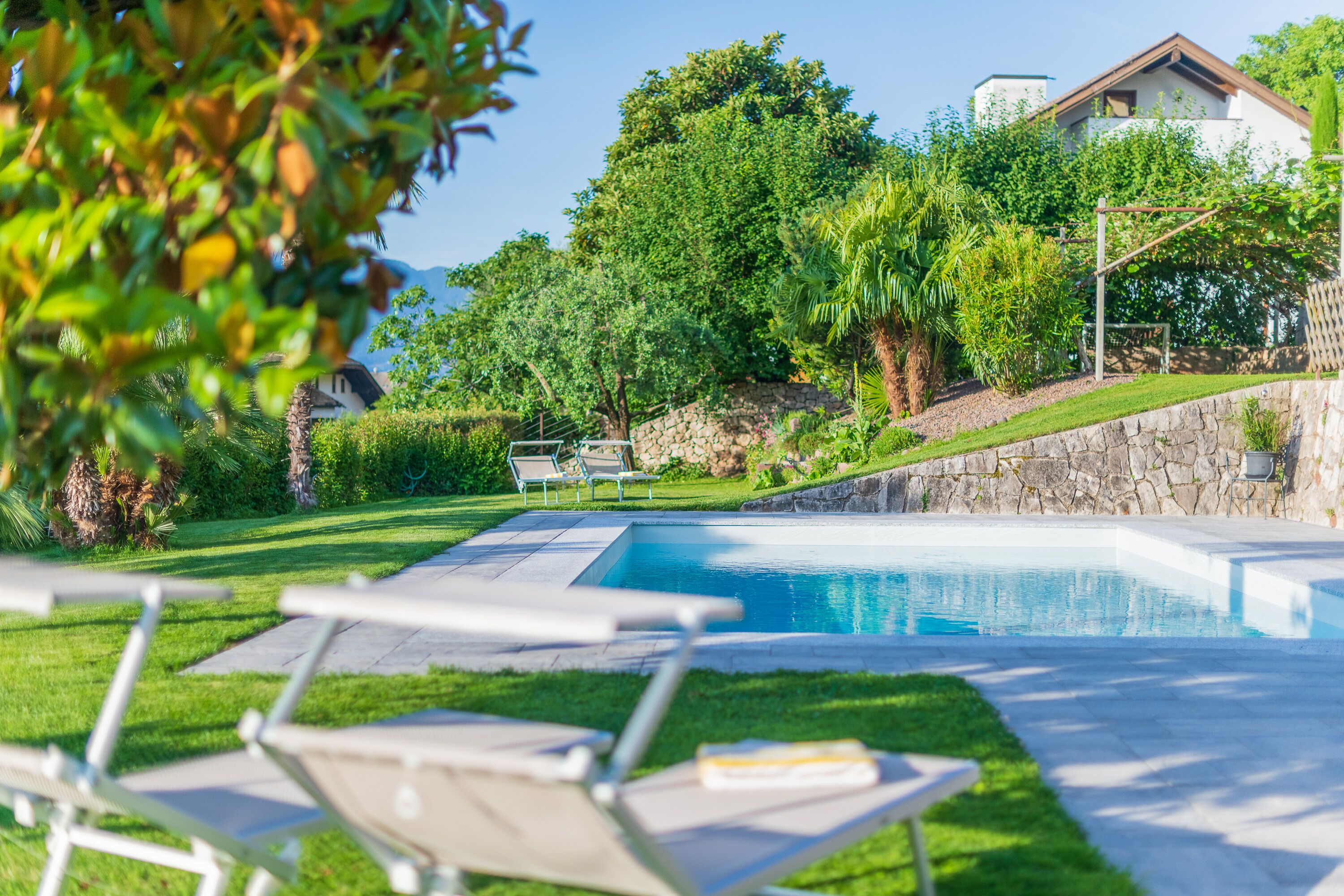 A swimming pool with lounge chairs, surrounded by a well-maintained lawn and trees.