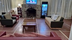 Una sala de estar con chimenea de piedra, dos sofás, una mesa de centro y un televisor sobre la chimenea.