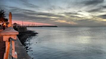 A coastal scene with a calm sea, a pier extending into the water, and a stone structure on the left.