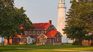 A lighthouse with a brick building in front, surrounded by trees. - Holiday Inn Express & Suites Port Huron by IHG (Port Huron)