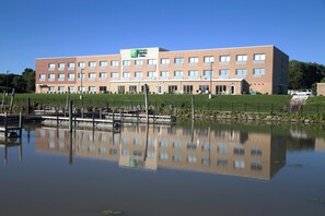 A multi-story hotel with a flat roof and a large parking area in front.
