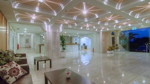 Un hall d’hôtel au design moderne, comprenant un comptoir d’accueil, un espace salon et une entrée en verre.