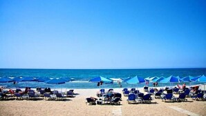 Une plage bordée de rangées de parasols bleus et de chaises longues.