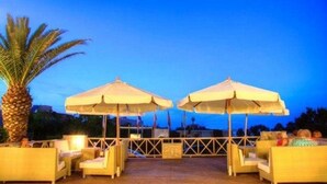 Un espace extérieur aménagé avec des parasols, des meubles en osier et un palmier.