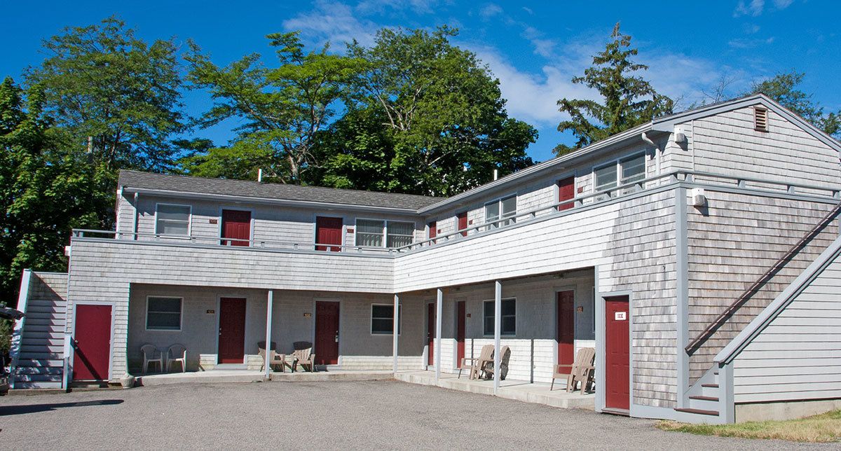 A two-story building with a central courtyard, multiple windows, and a red door.