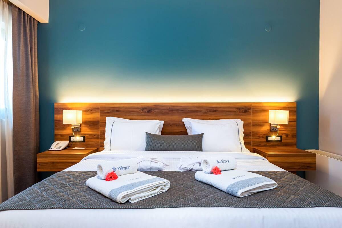 A hotel room with a large bed, two bedside lamps, a wooden headboard, and a telephone on the nightstand.