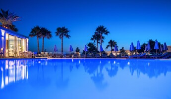 Una piscina al aire libre, sombrillas, sillones reclinables de piscina