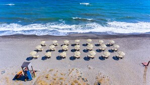 Vista aérea de una playa con filas de sillas y sombrillas dispuestas para tomar el sol.
