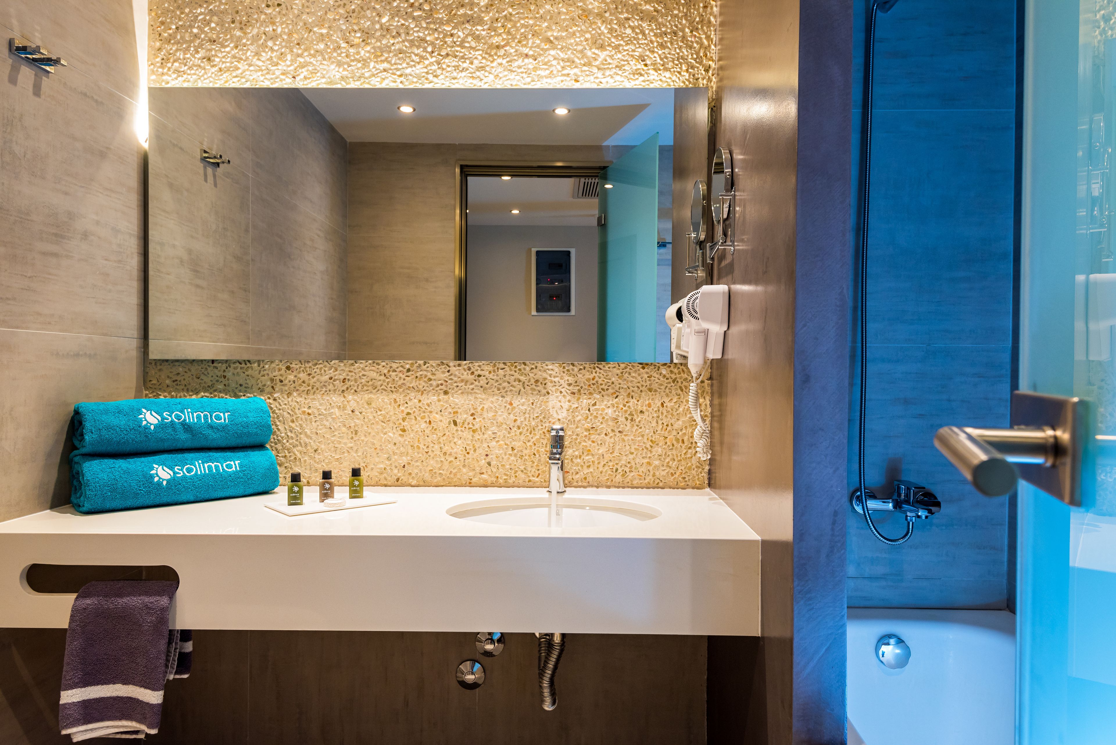 A modern bathroom with a large mirror, a sink, and a shower area.