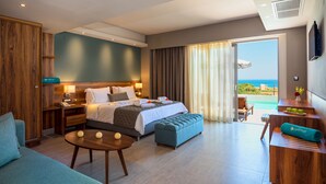 Habitación de hotel con cama, sofá, una mesita y vista al océano.
