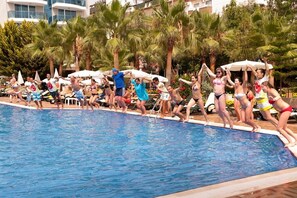 A pool area with people jumping into the water, surrounded by palm trees and lounge chairs. - Concordia Celes Beach Hotel - Ultra All Inclusive (Alanya)