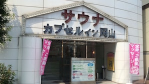 A building with a sign that reads "Sasa" and "Cafe & Restaurant". There are two pink banners on either side of the entrance. - Sauna & Capsule In Okayama (Okayama)