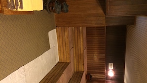 A wooden interior with a bench, a wall-mounted rack, and a small illuminated sign. - Sauna & Capsule In Okayama (Okayama)