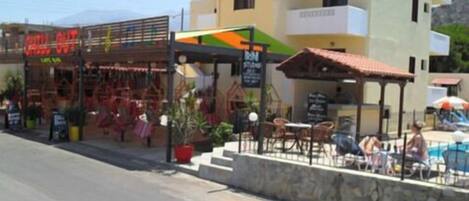 A building with a sign reading "IRINI" and a restaurant named "CHILI OUT" with outdoor seating.
