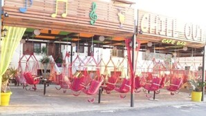 En cafébar med en träfasad och röda hängmattor som hänger utanför.
