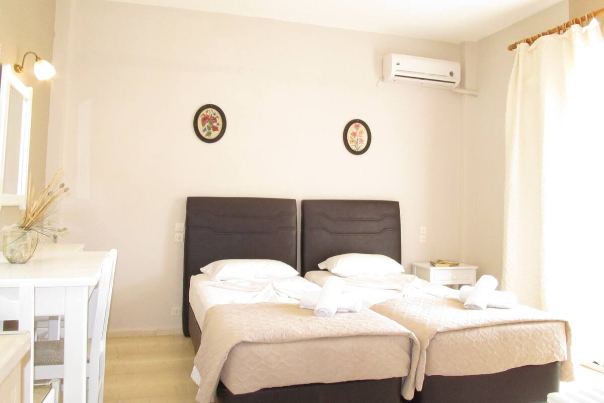 Habitación de hotel con dos camas, un escritorio y un equipo de aire acondicionado.