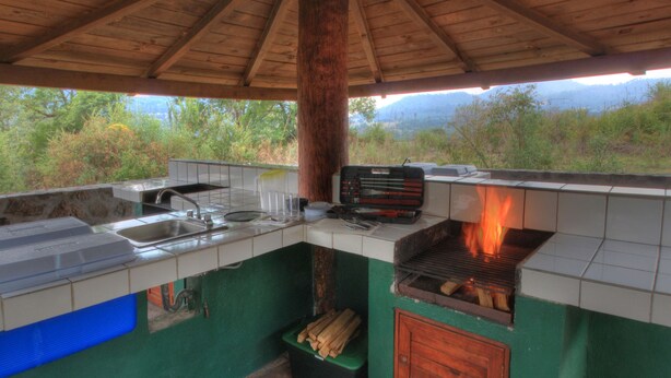 An outdoor kitchen with a grill, sink, and storage for cooking utensils. - Cabañas El Estribo Hotel (Valle de Bravo)