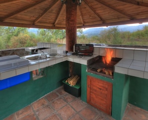 An outdoor kitchen with a grill, sink, and storage for cooking utensils. - Cabañas El Estribo Hotel (Valle de Bravo)