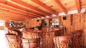 A rustic bar area with wooden bar stools and a tiled floor. - Cabañas El Estribo Hotel (Valle de Bravo)
