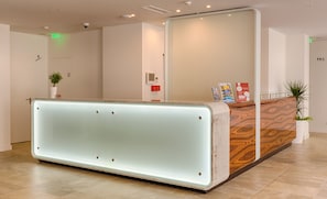 A reception desk with a lighted panel, a plant, and informational posters. - Porto Downtown (Porto)