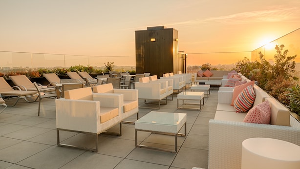 A rooftop lounge area with multiple seating options, including lounge chairs and sofas, arranged on a tiled floor. - Porto Downtown (Porto)