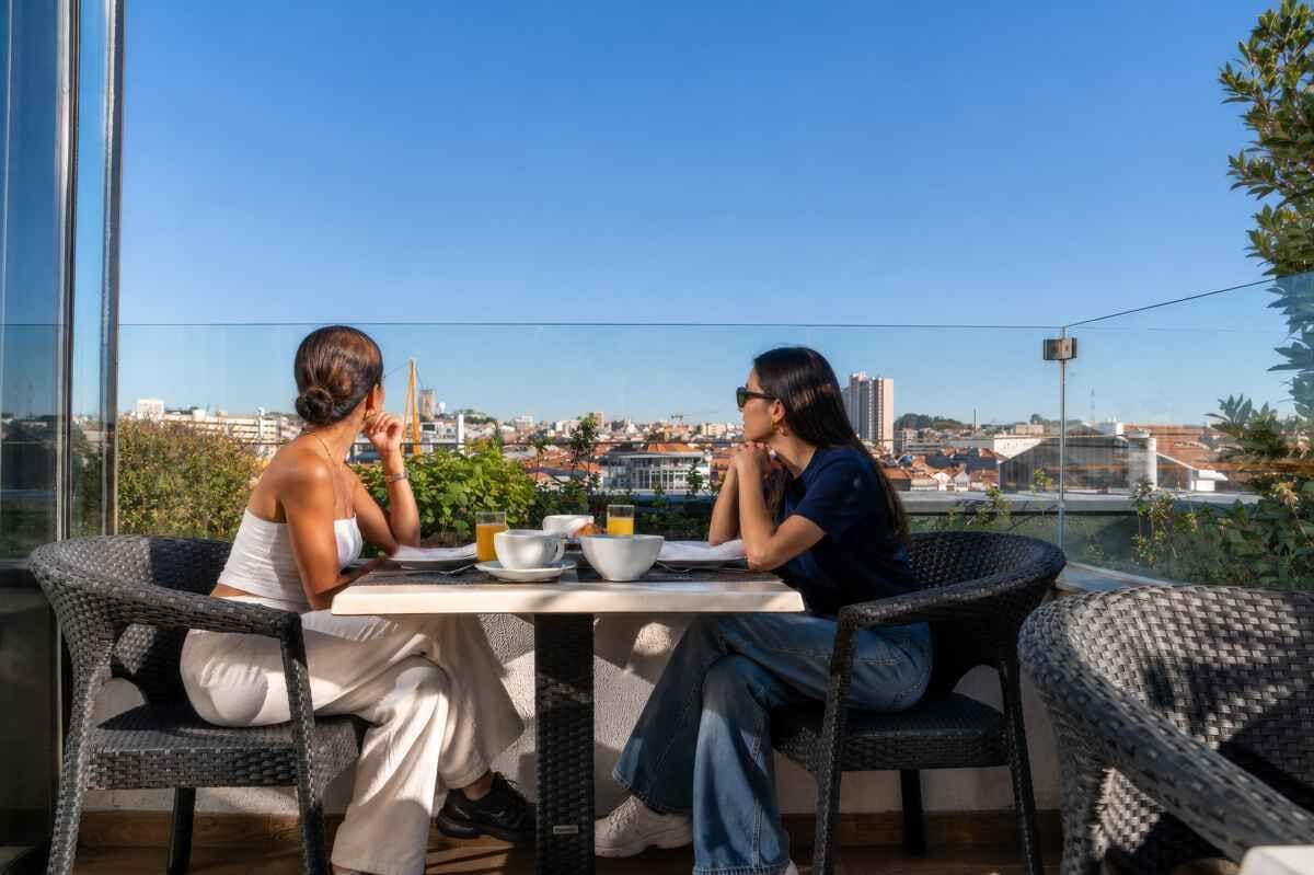 Two people dining at an outdoor table with a city view.