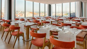 A spacious dining area with multiple tables and chairs, large windows offering a city view. - Porto Downtown (Porto)