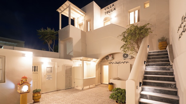 A villa named "Villa Toula" with a staircase leading to the upper floor, potted plants, and a reception area. - Villa Toula (Santorini)