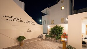 A courtyard with patterned flooring, a small staircase, a wall-mounted ship decoration, and a potted plant. - Villa Toula (Santorini)