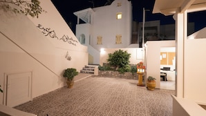 A courtyard with a tiled floor, a staircase, and a building with a white facade. - Villa Toula (Santorini)