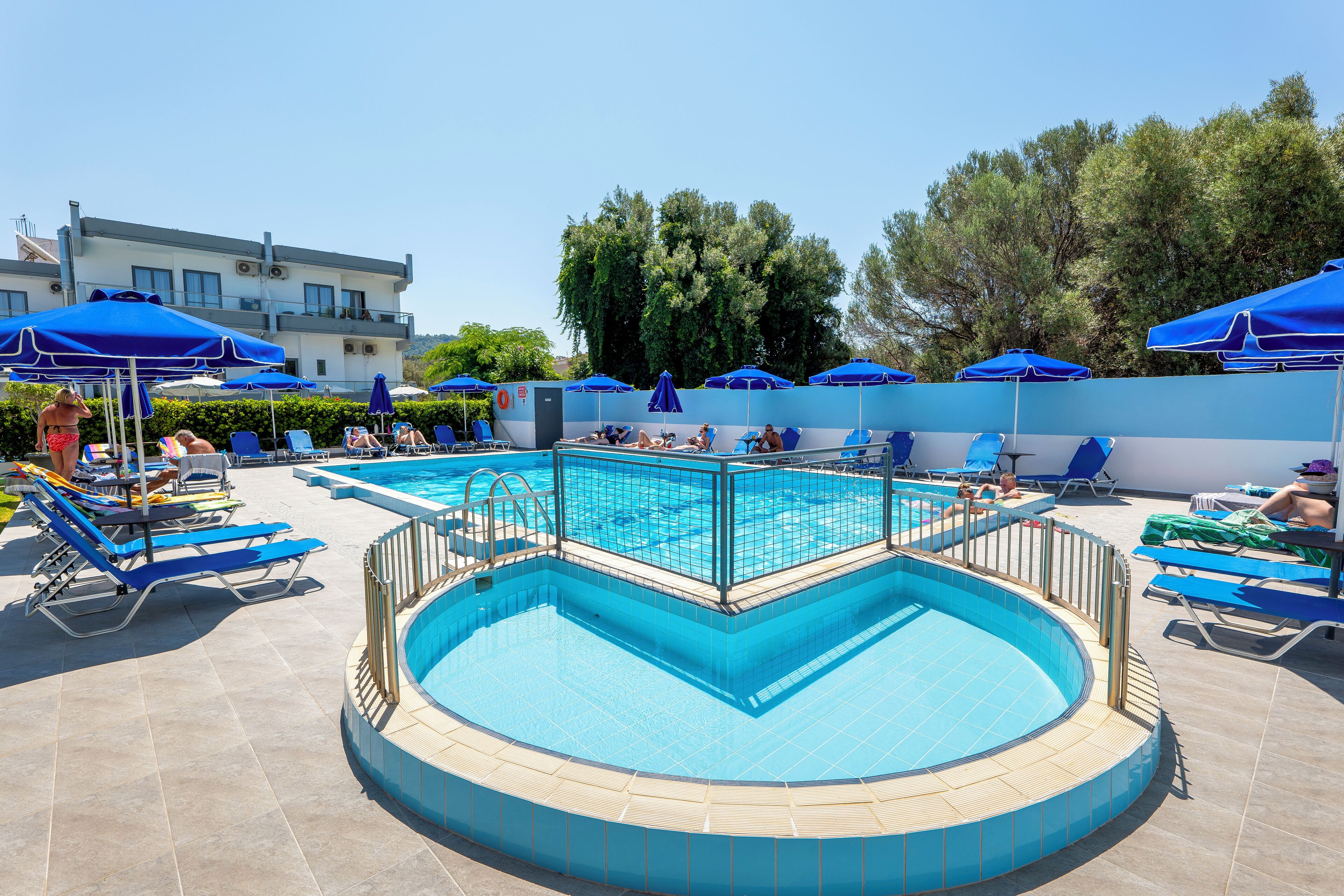 Piscina com bordas azuis e azulejos, rodeada por espreguiçadeiras e guarda-sóis azuis.