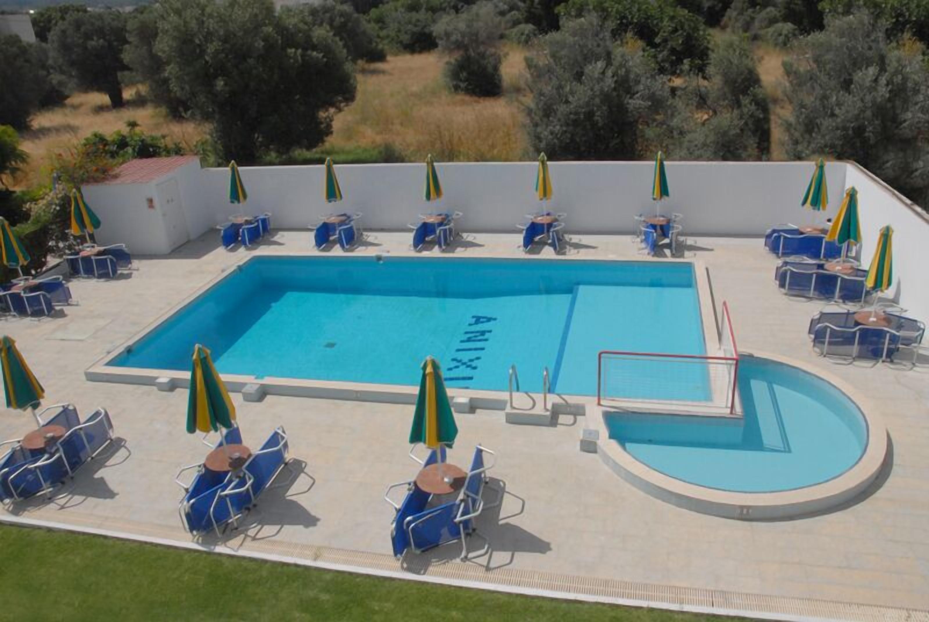 A rectangular swimming pool with a surrounding deck, equipped with multiple lounge chairs and umbrellas.