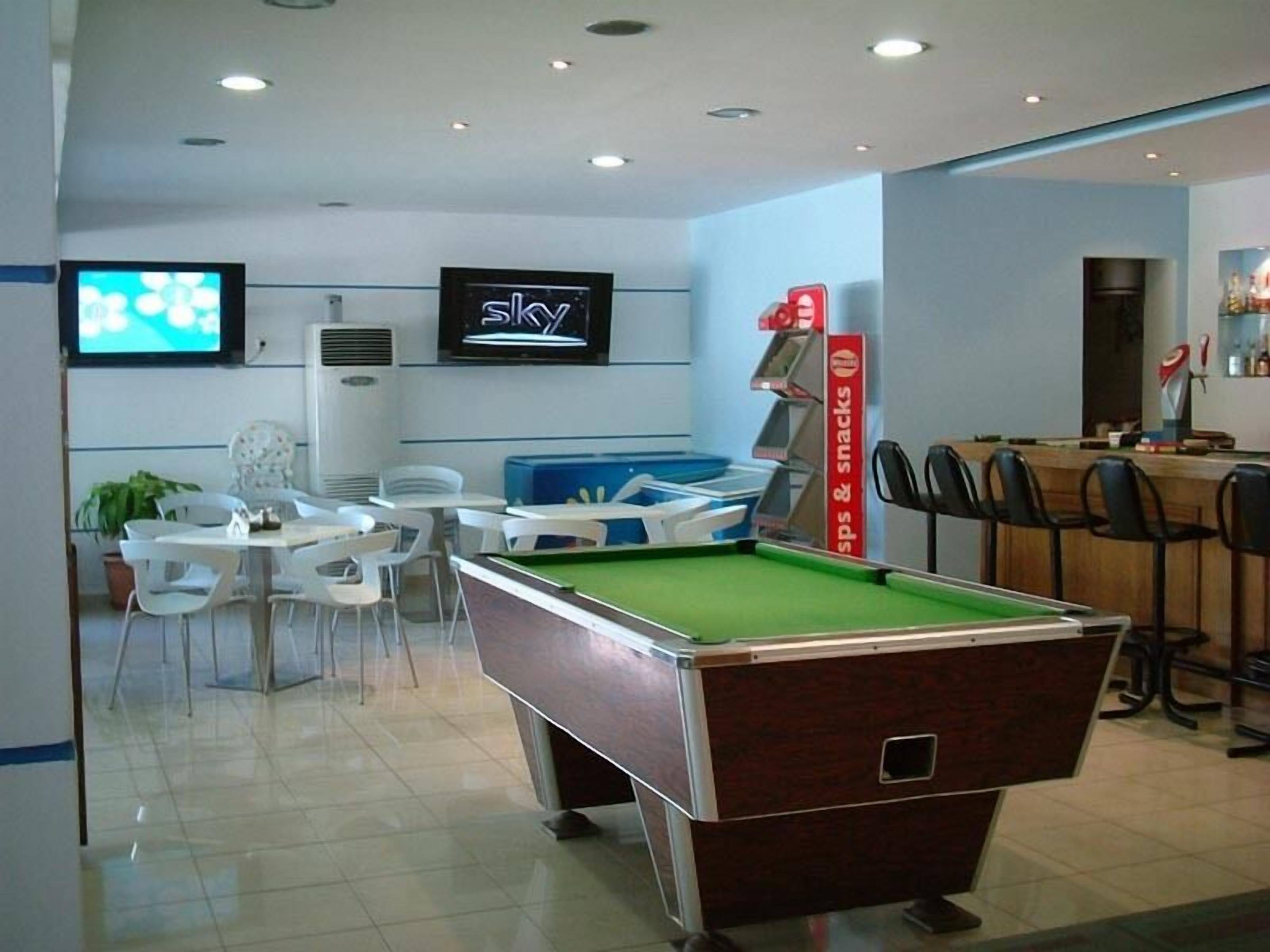 A pool table in a room with a television displaying 'Sky' and a snack bar.